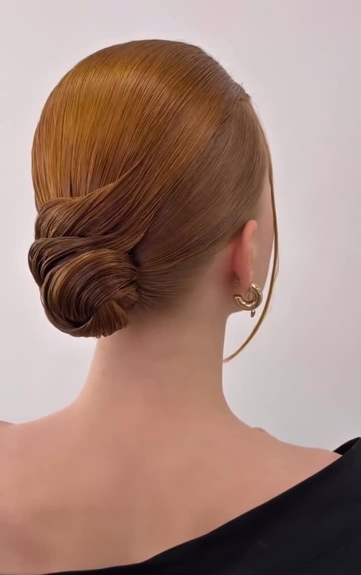17 Wedding Guest Hairstyles Up: From Curled Updos to Bubble Braids 4 A woman with smooth, light brown hair styled in a polished low sleek bun.