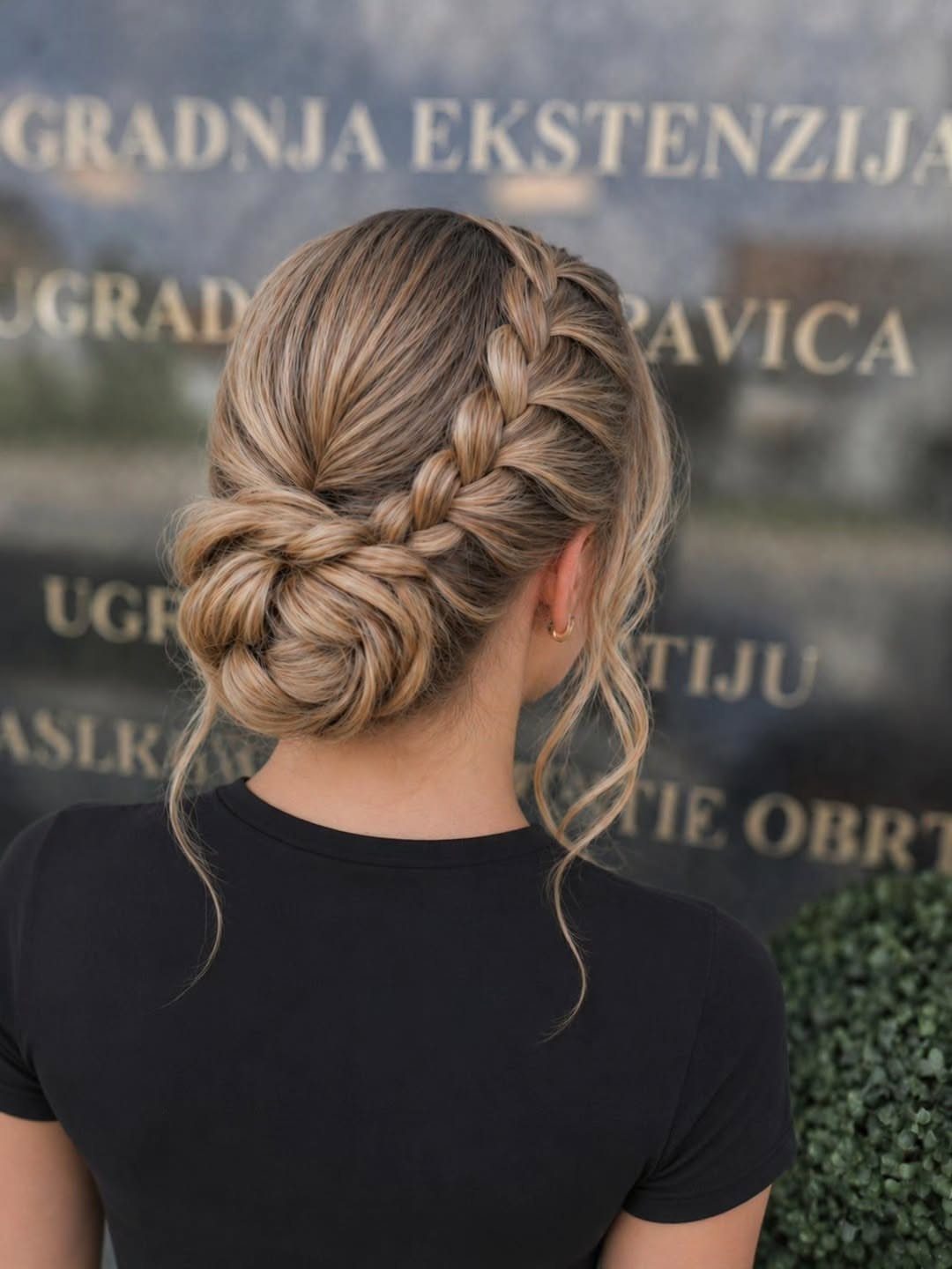 Blonde hair styled in a low bun with a thick center Dutch braid.