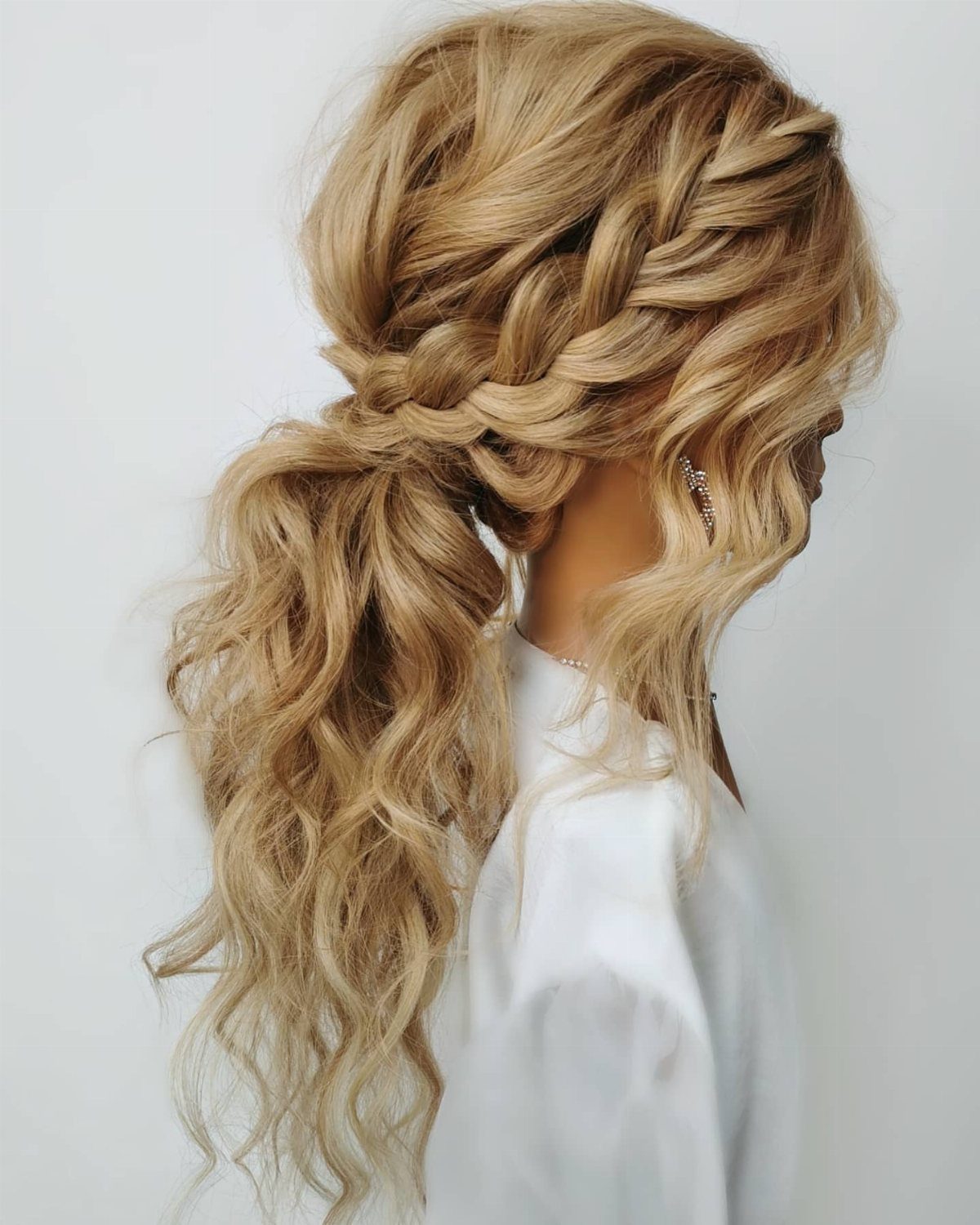 Blonde curly hair styled in a low ponytail with a crown braid.