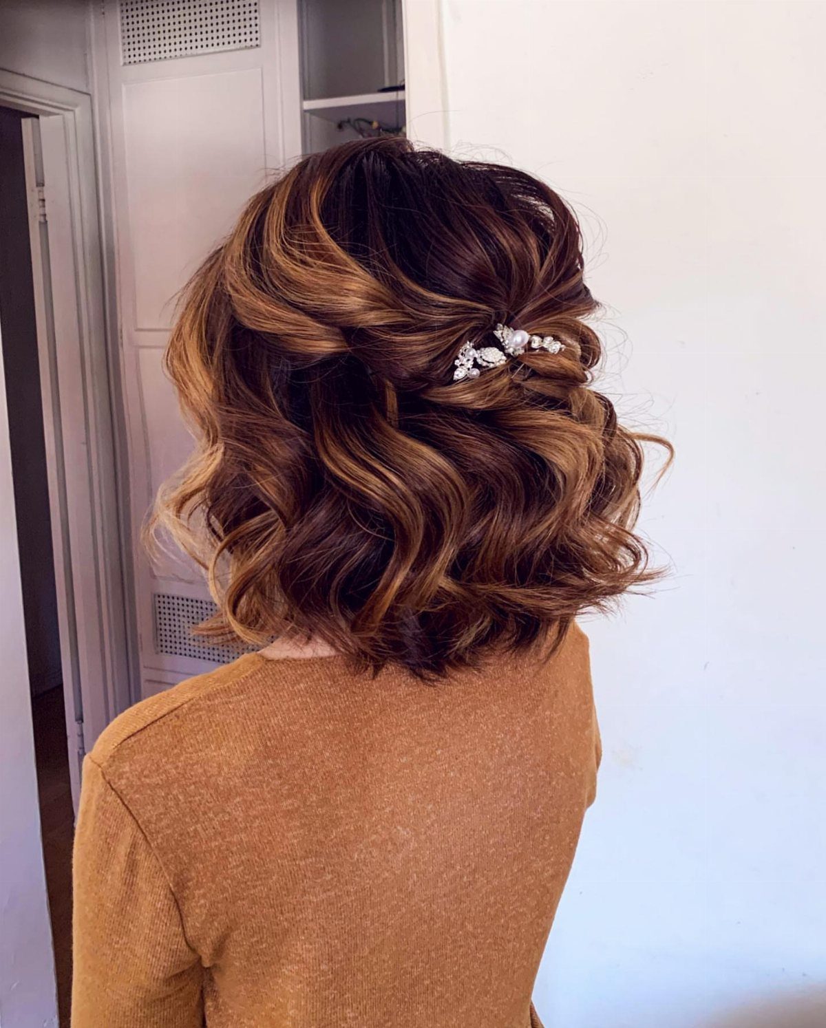 Chin-length wavy brown hair in a half-updo with a silver decorative hair clip.