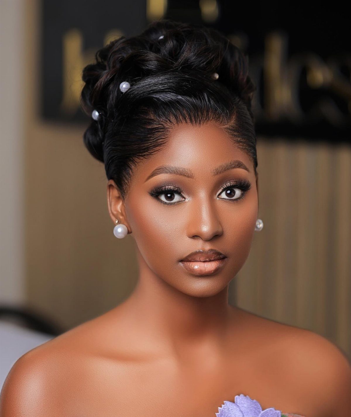 Woman with a polished high bun hairstyle decorated with small white pearls.