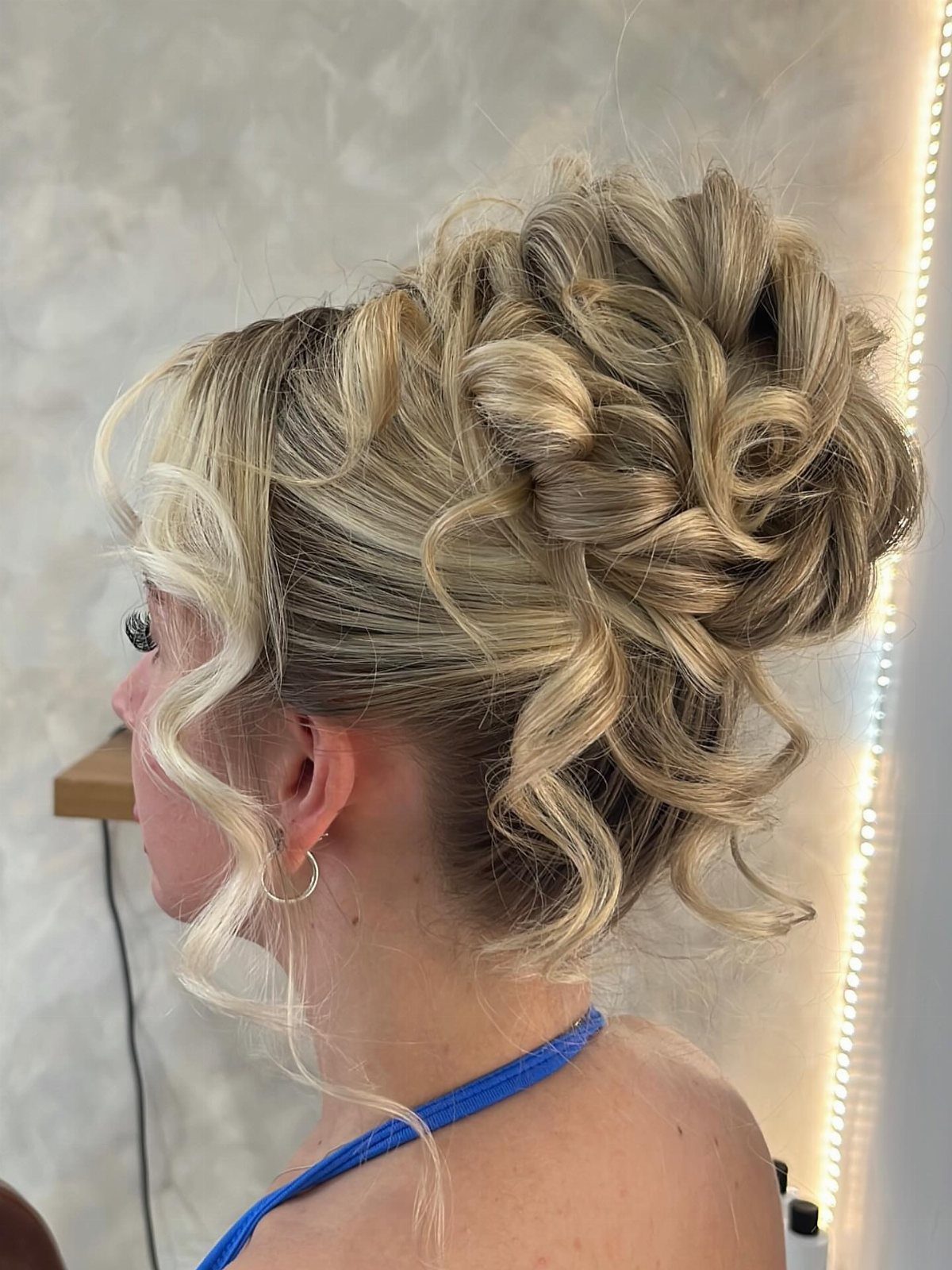 Blonde hair styled in a voluminous curly loose bun with face-framing curls.