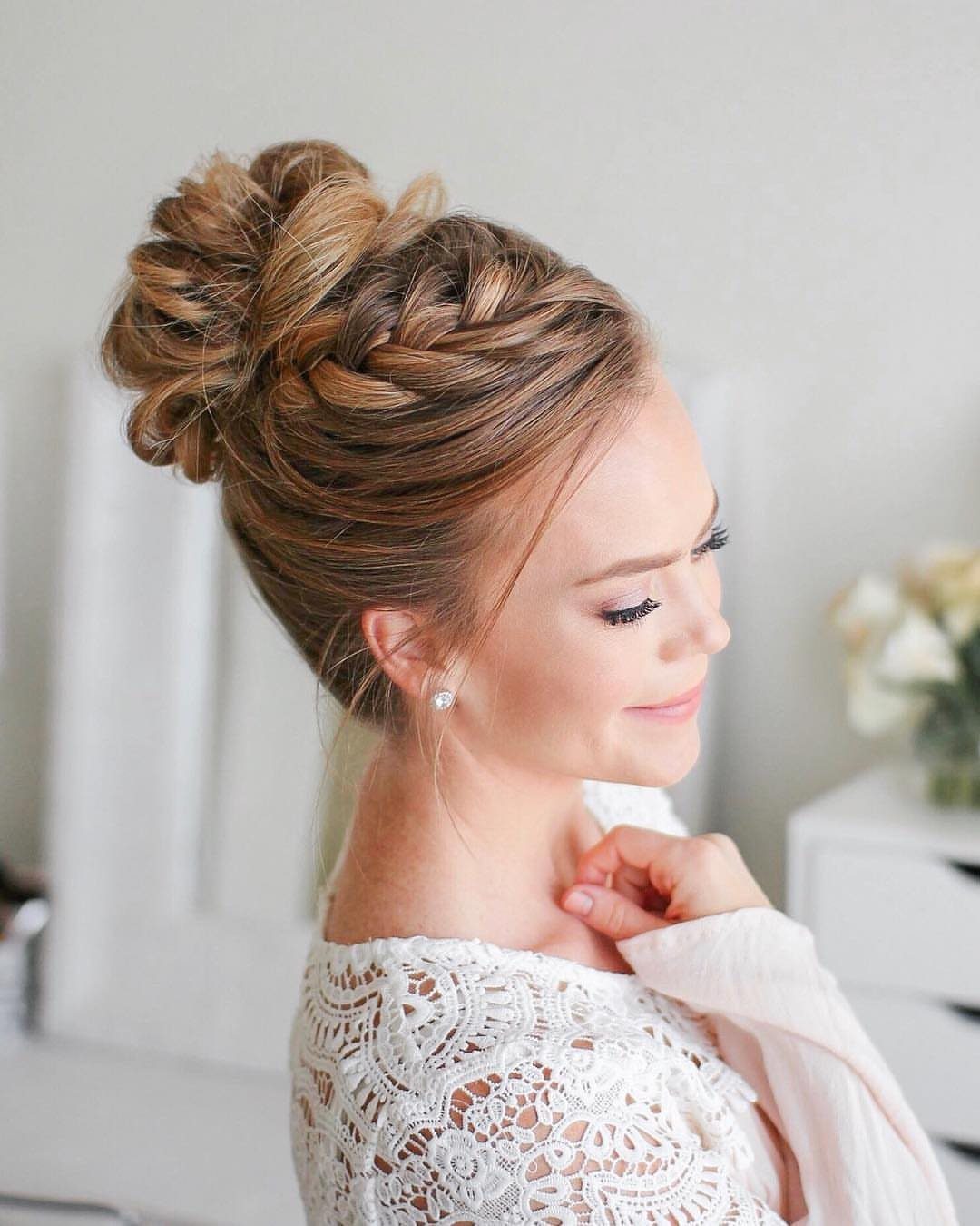 Woman with a braided high bun and white lace dress posing in profile.