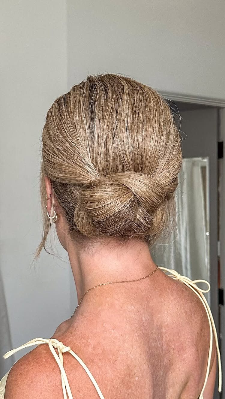Blonde hair styled in a polished low bun at the nape of the neck.