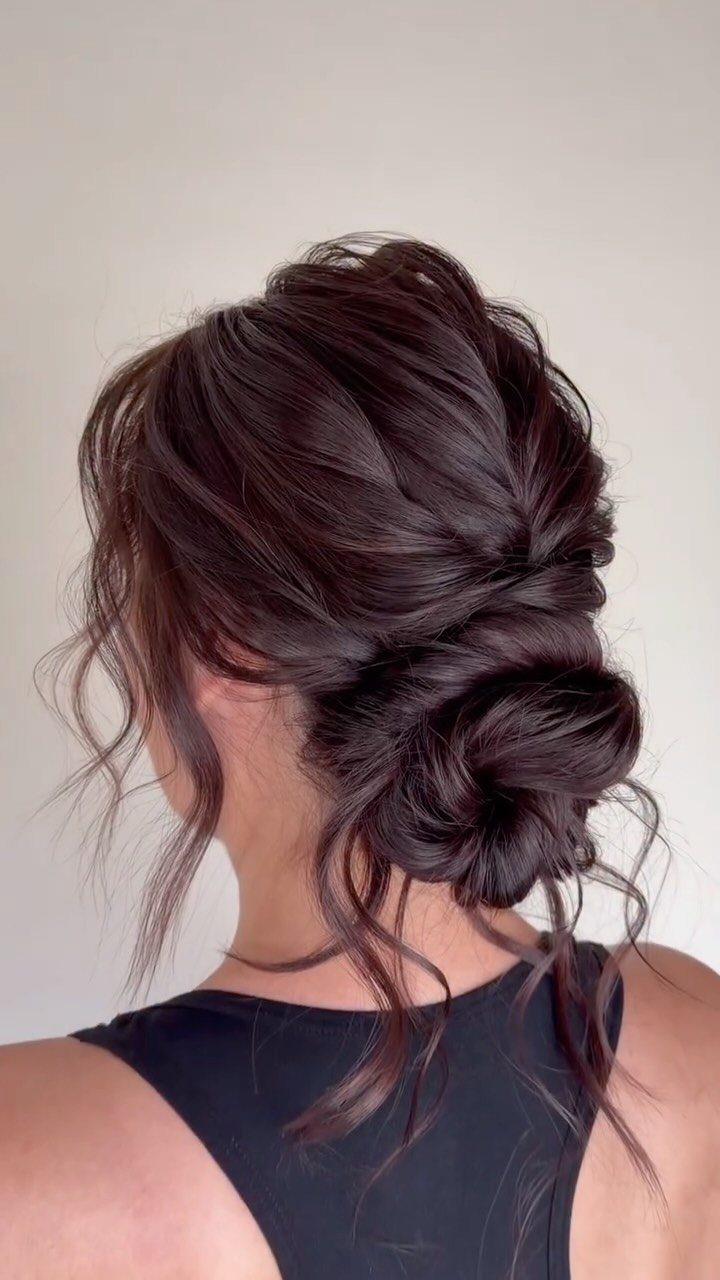 Dark brown hair styled in a textured low messy bun with loose wisps.