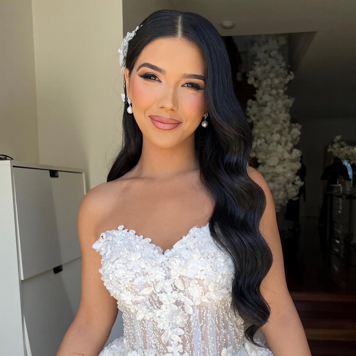 Woman with long dark wavy hair and a middle part wearing a wedding dress.