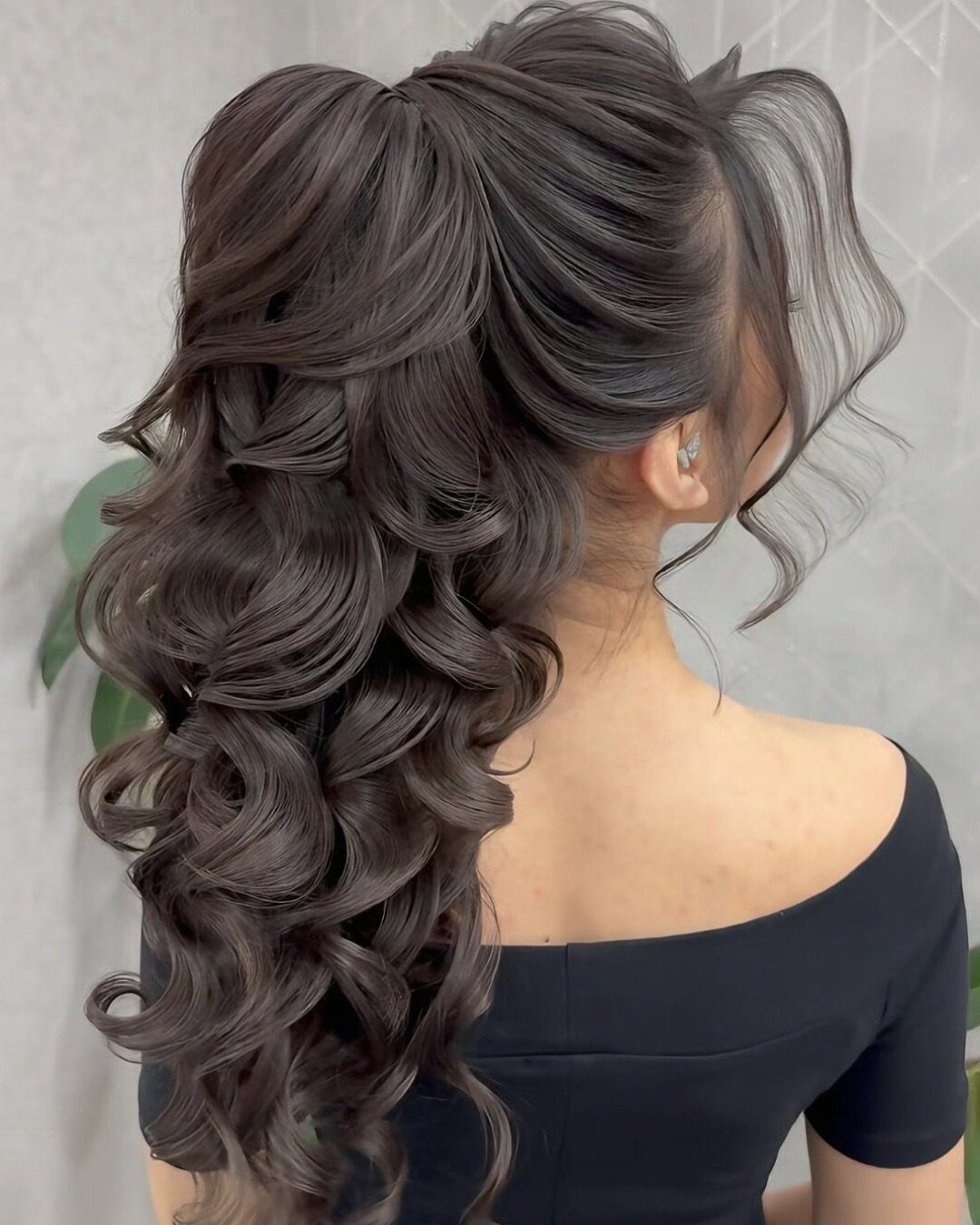 Voluminous ash-brown curly hair styled in a side ponytail draped over the shoulder.