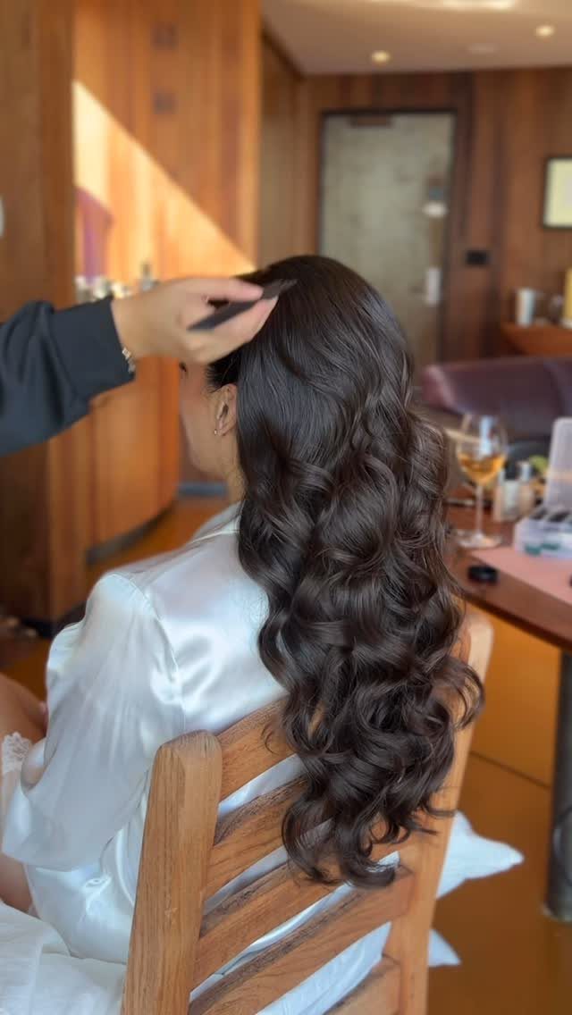Woman with long dark brown soft curls wearing a white satin robe.