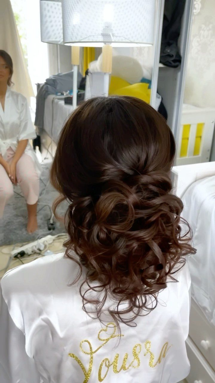Dark brown curly hair styled in a voluminous low updo on a person.