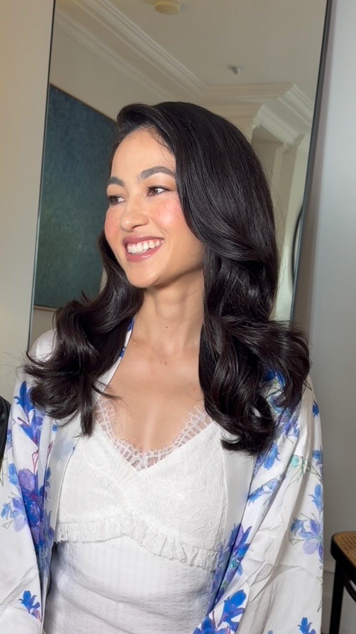 Woman with voluminous, bouncy dark brown blowout hair smiling in a floral robe.