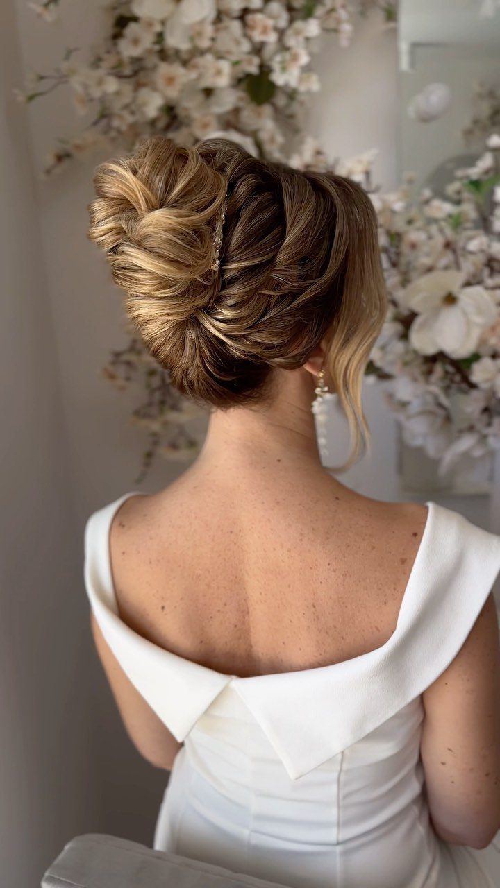 Blonde woman with a textured voluminous updo wearing a white off-the-shoulder dress