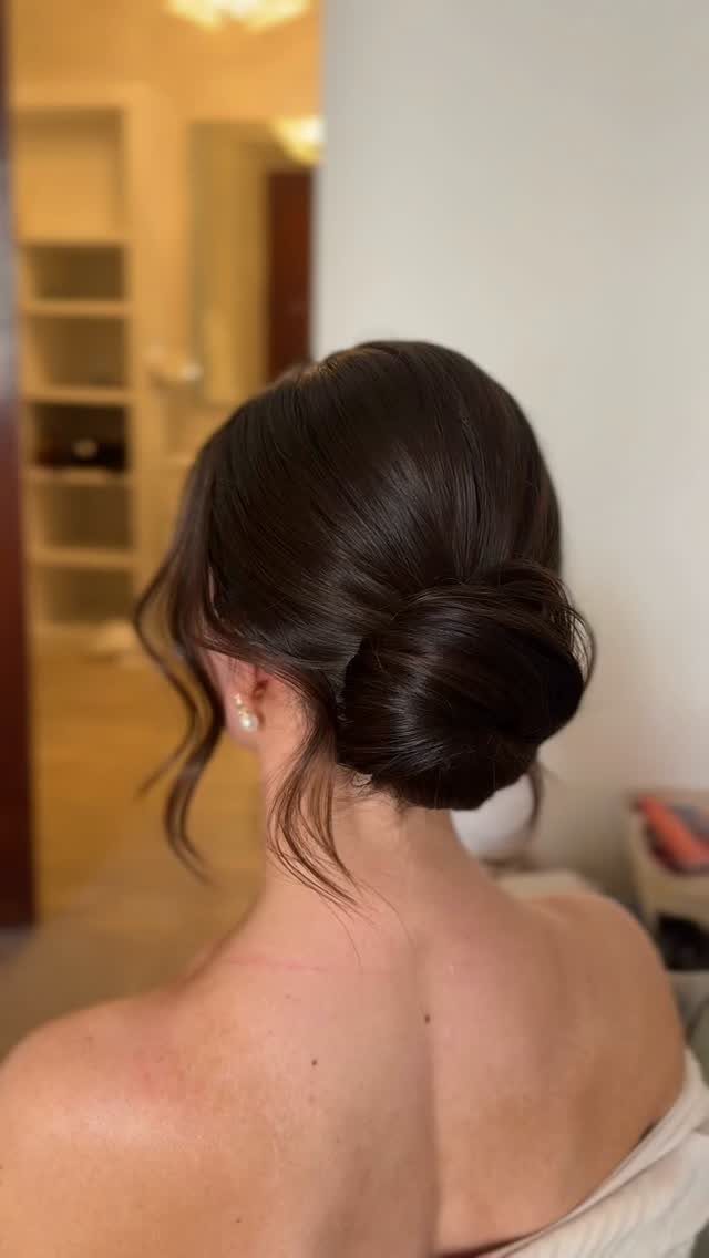 Dark brown hair styled in a smooth low chignon bun at the nape.