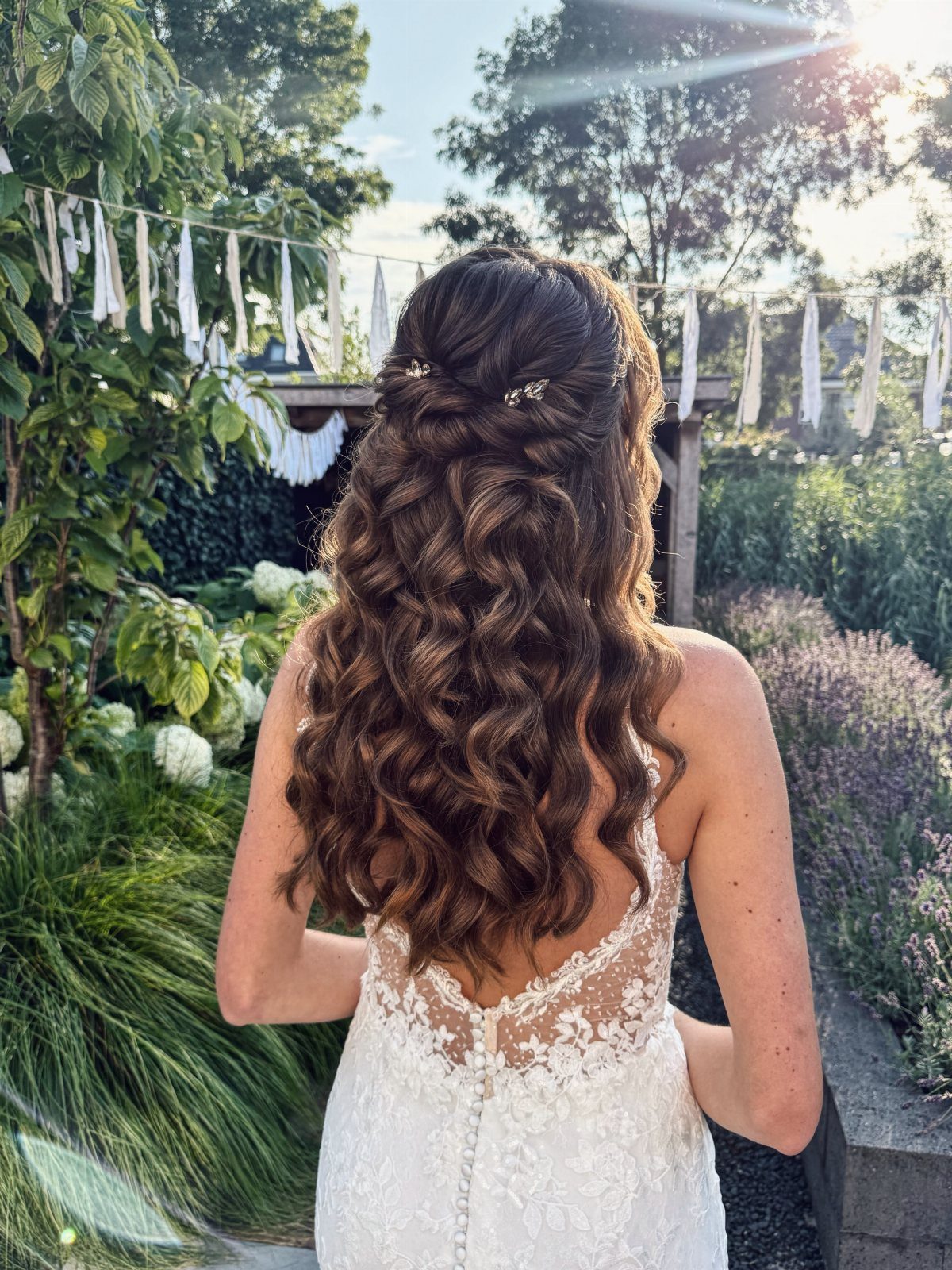 Woman with medium brown hair in soft curls wearing a white lace wedding dress