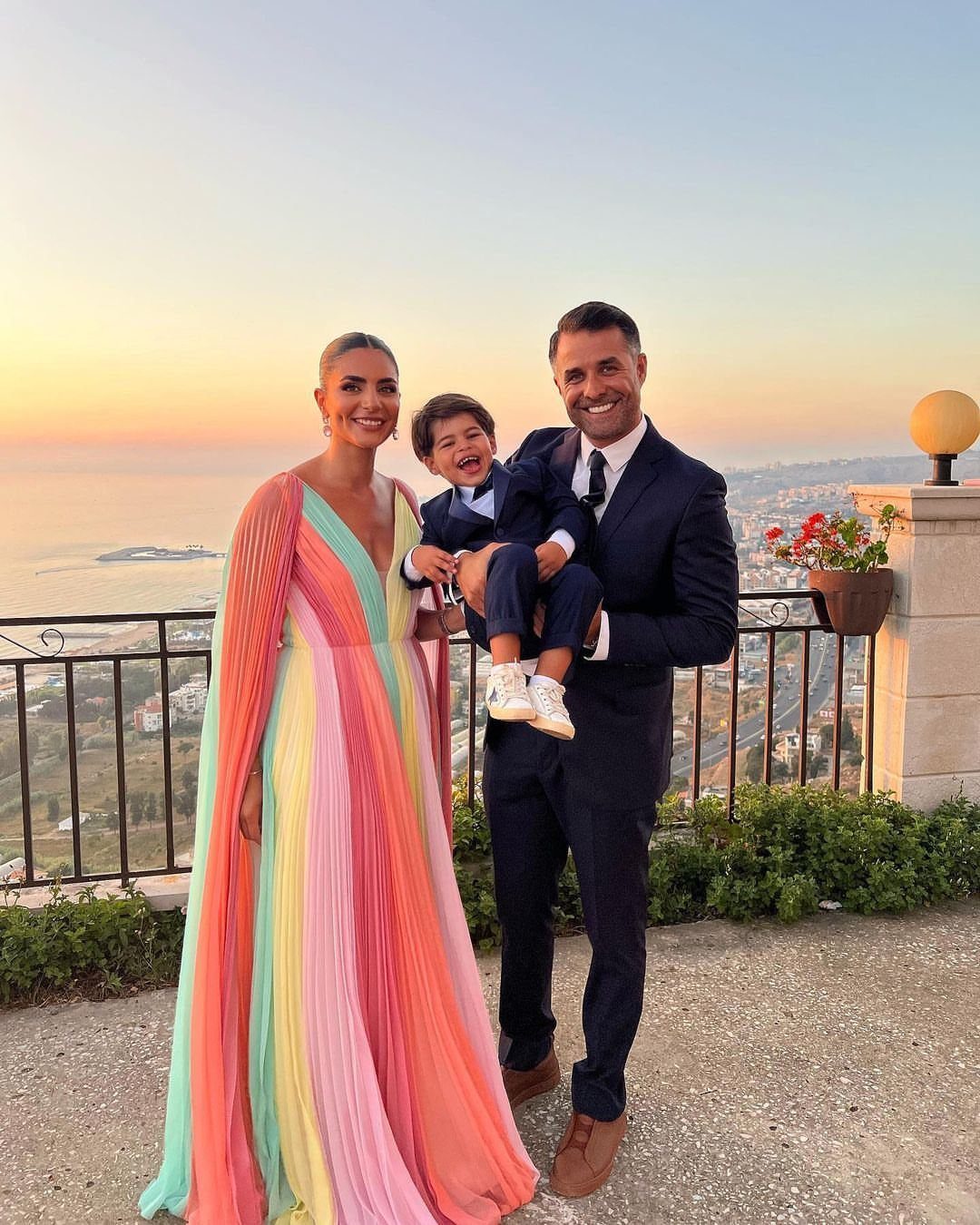 Wedding Outfit Outdoor: 9 Guest Looks for Every Setting 7 A family posing outdoors at sunset, featuring a woman in a colorful pleated maxi dress.