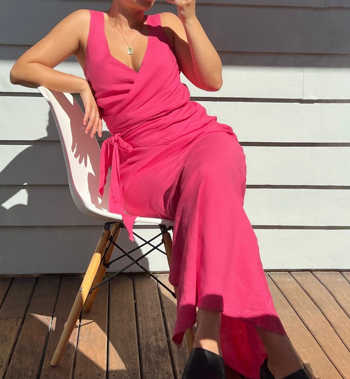 Wedding Outfit Outdoor: 9 Guest Looks for Every Setting 5 Woman sitting on a white chair wearing a long pink wrap dress outdoors.