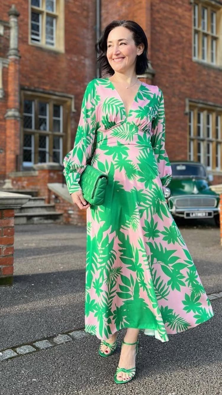 Wedding Outfit Outdoor: 9 Guest Looks for Every Setting 3 Woman wearing a green and pink palm print maxi dress and matching green sandals outdoors.