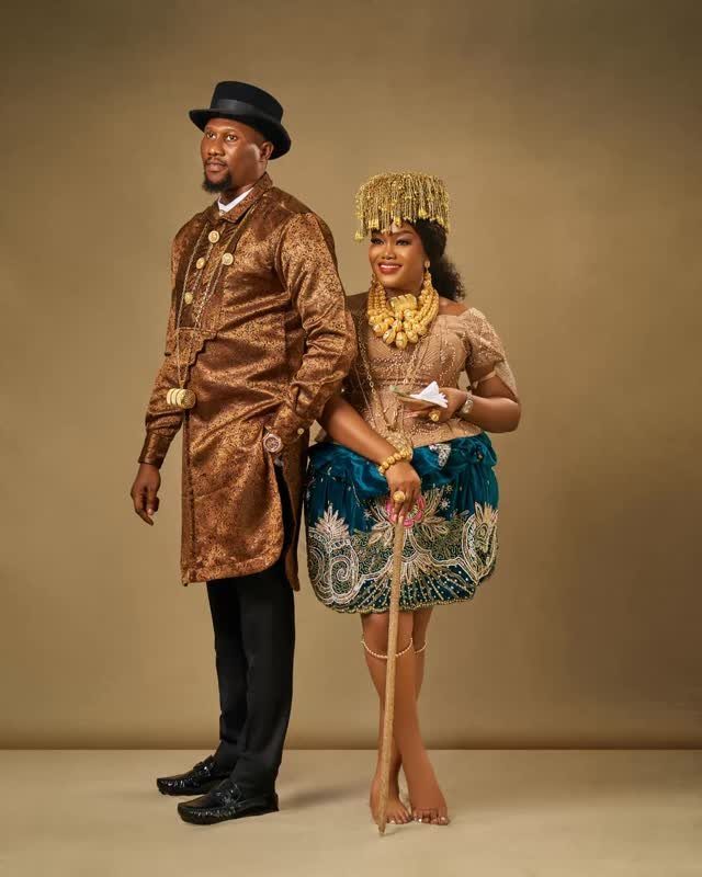 A man and woman posing in ornate traditional gold jewelry and patterned clothing.