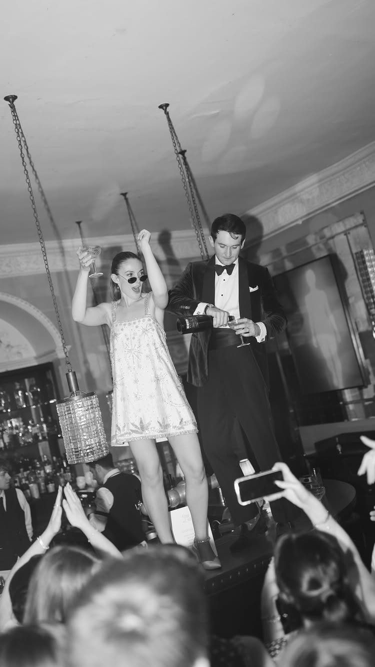 18 Wedding Outfit Theme Ideas for 2026: Beach, Boho, Gatsby & More 9 A man in a tuxedo and a woman in a sequined dress dancing in a club.