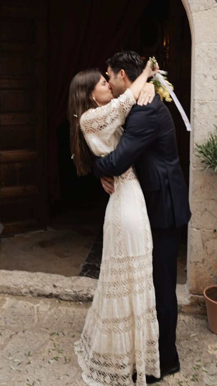 18 Wedding Outfit Theme Ideas for 2026: Beach, Boho, Gatsby & More 5 A bride in lace and a groom in a dark suit kissing outdoors.