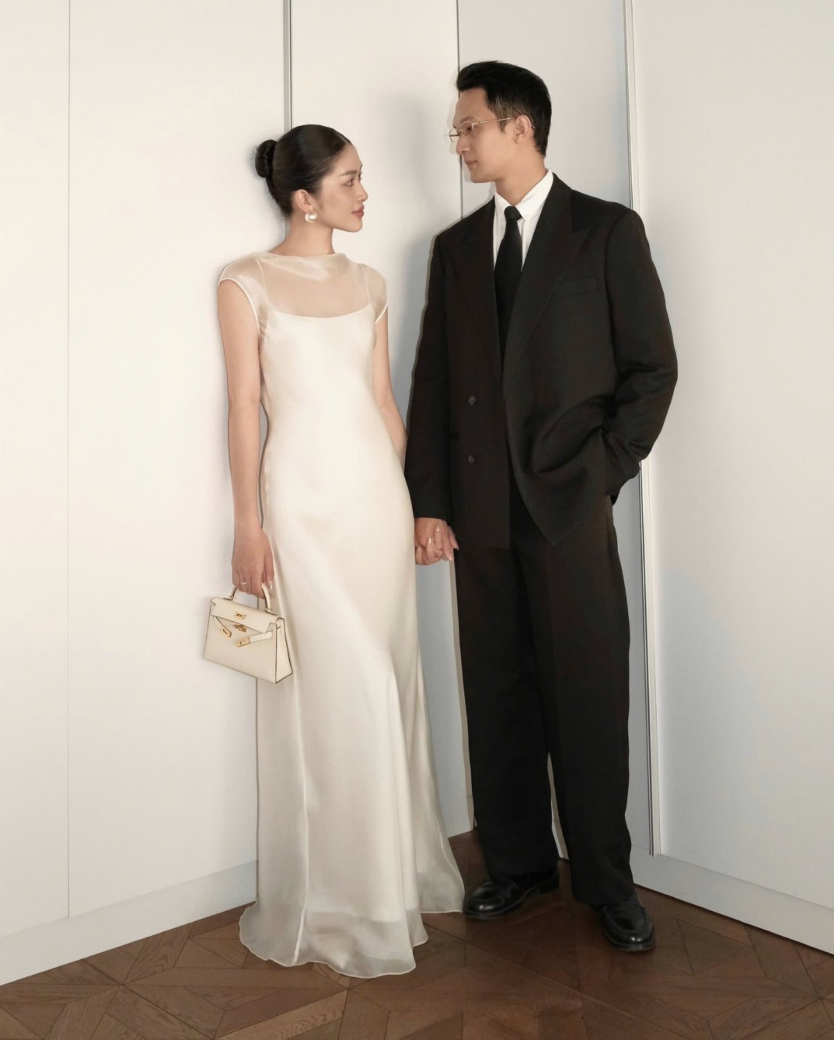 18 Wedding Outfit Theme Ideas for 2026: Beach, Boho, Gatsby & More 4 A woman in a white gown and a man in a black suit stand together.