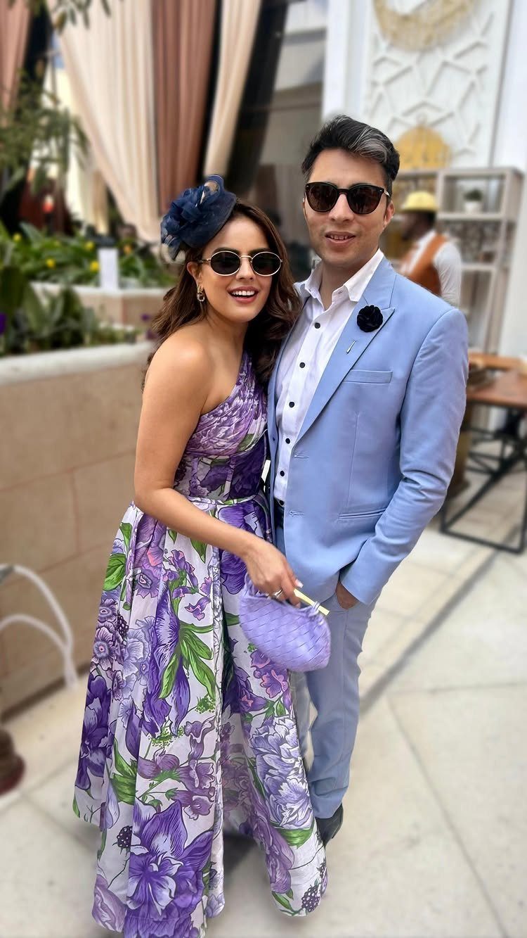 18 Wedding Outfit Theme Ideas for 2026: Beach, Boho, Gatsby & More 17 A woman in a purple floral gown and a man in a light blue suit posing together.