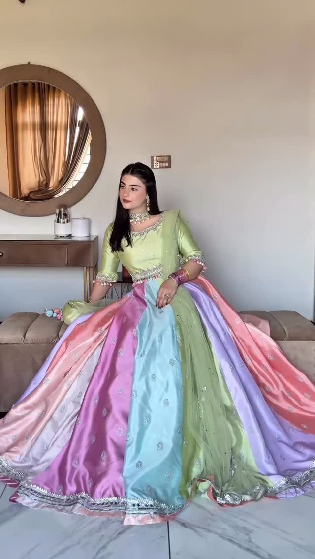 18 Wedding Outfit Theme Ideas for 2026: Beach, Boho, Gatsby & More 10 Woman in a multi-colored pastel lehenga sitting on a brown couch indoors.