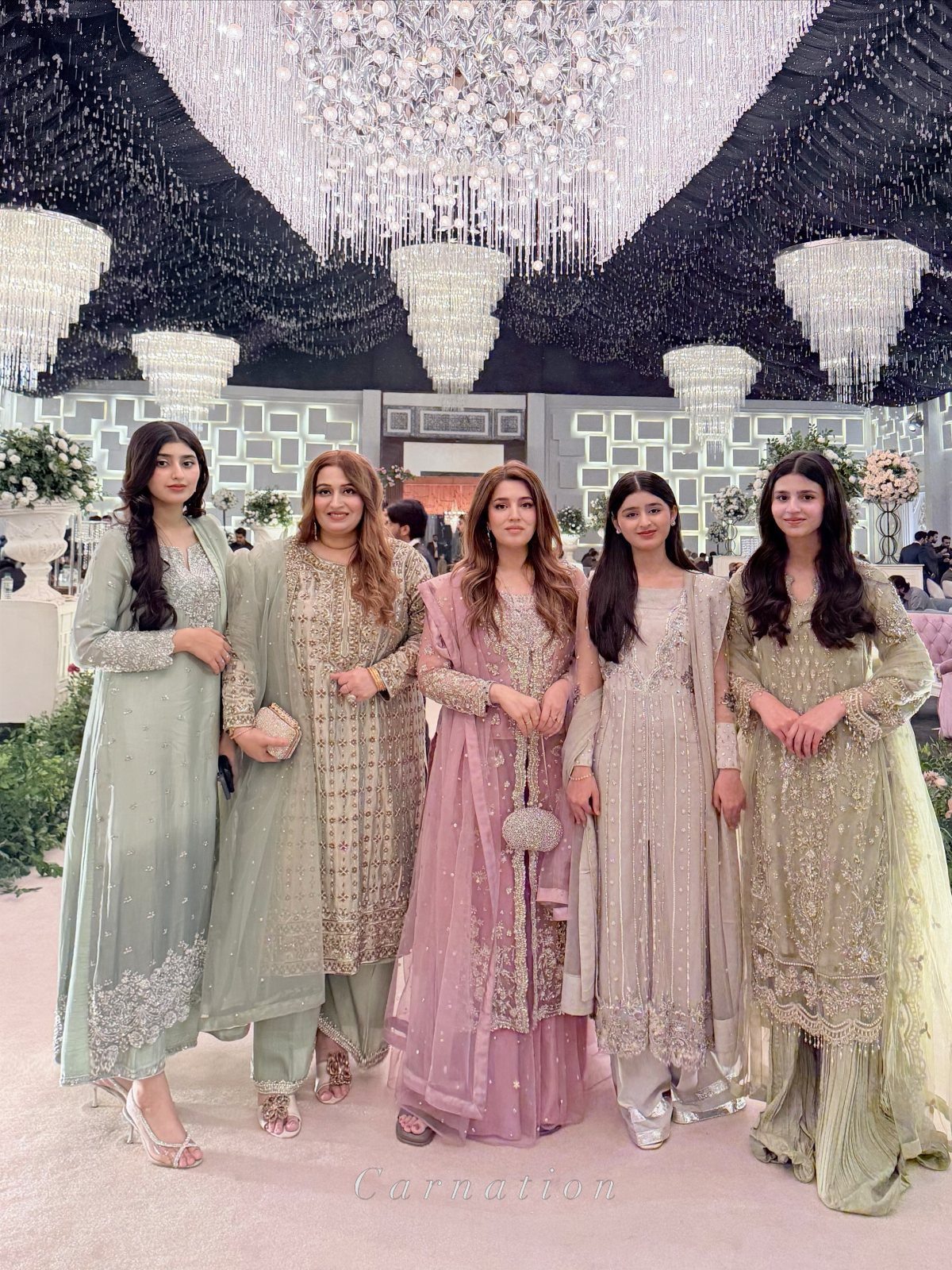 Wedding Party Colors: 13 Real Palette Ideas for Your Bridal Party 8 Five women posing in elegant, embroidered traditional dresses in pastel green, gold, and pink tones.