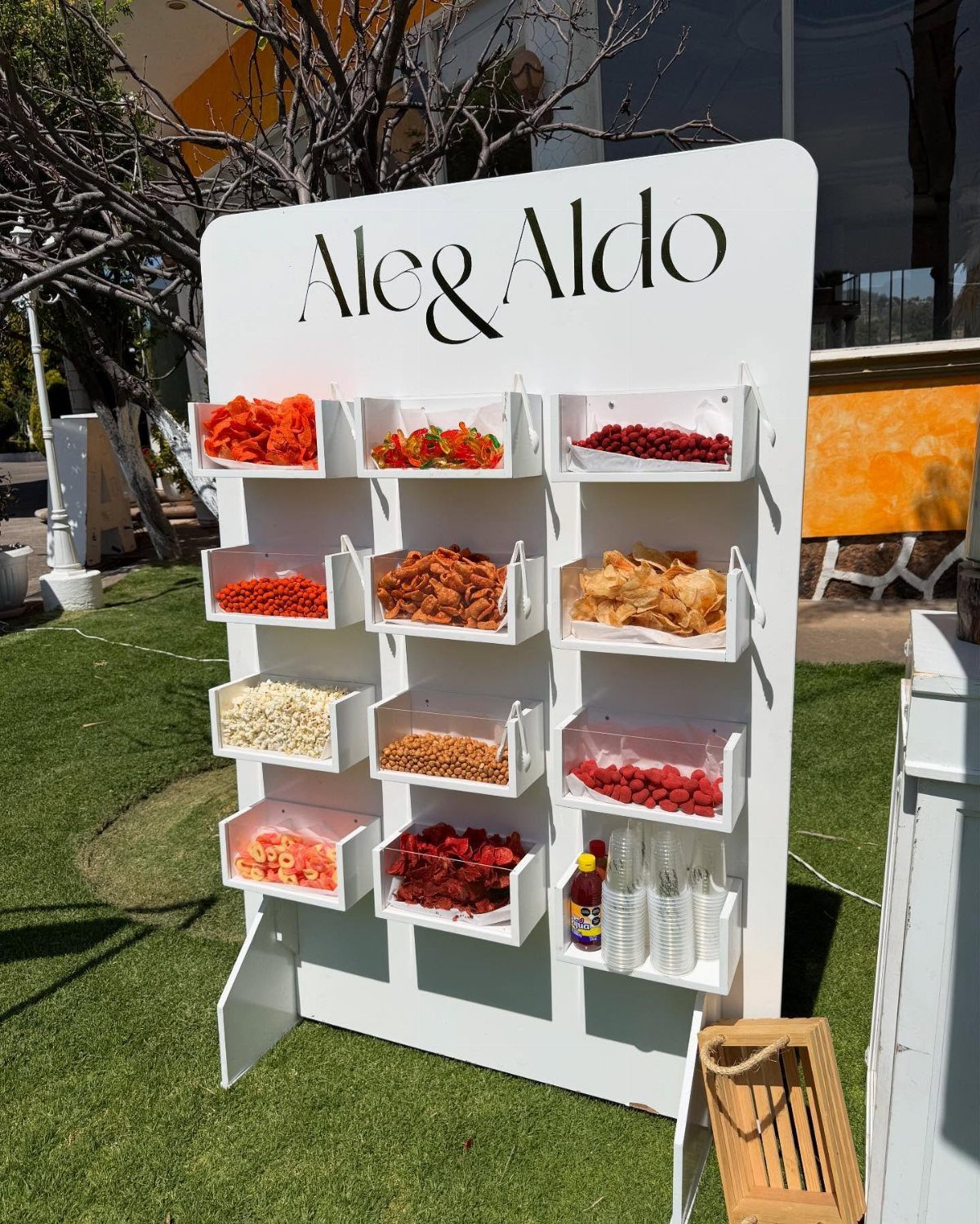 10 Wedding Party Ideas for an Unforgettable Night 8 White snack display stand with clear bins filled with various colorful dried fruits and nuts outdoors.