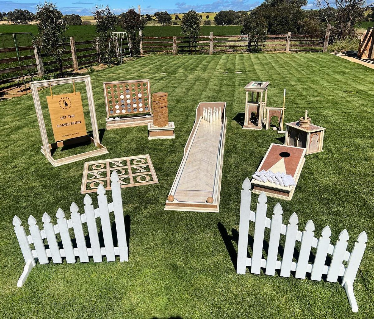 10 Wedding Party Ideas for an Unforgettable Night 6 Wooden lawn games arranged on a green grass lawn with small white picket fences.
