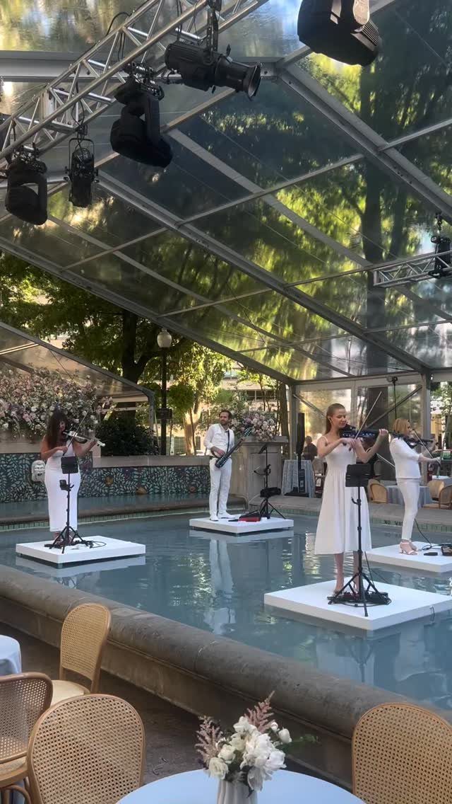 10 Wedding Party Ideas for an Unforgettable Night 3 Musicians in white performing on platforms inside a shallow pool under a clear tent.