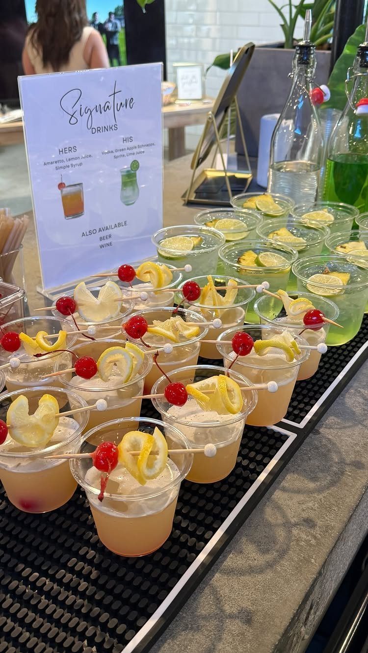 10 Wedding Party Ideas for an Unforgettable Night 9 Small cocktail cups with lemon and cherry garnishes arranged on a black tray near a drink menu.