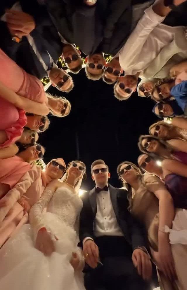 10 Wedding Party Ideas for an Unforgettable Night 11 A wedding party looking down into the camera lens while wearing sunglasses at night.