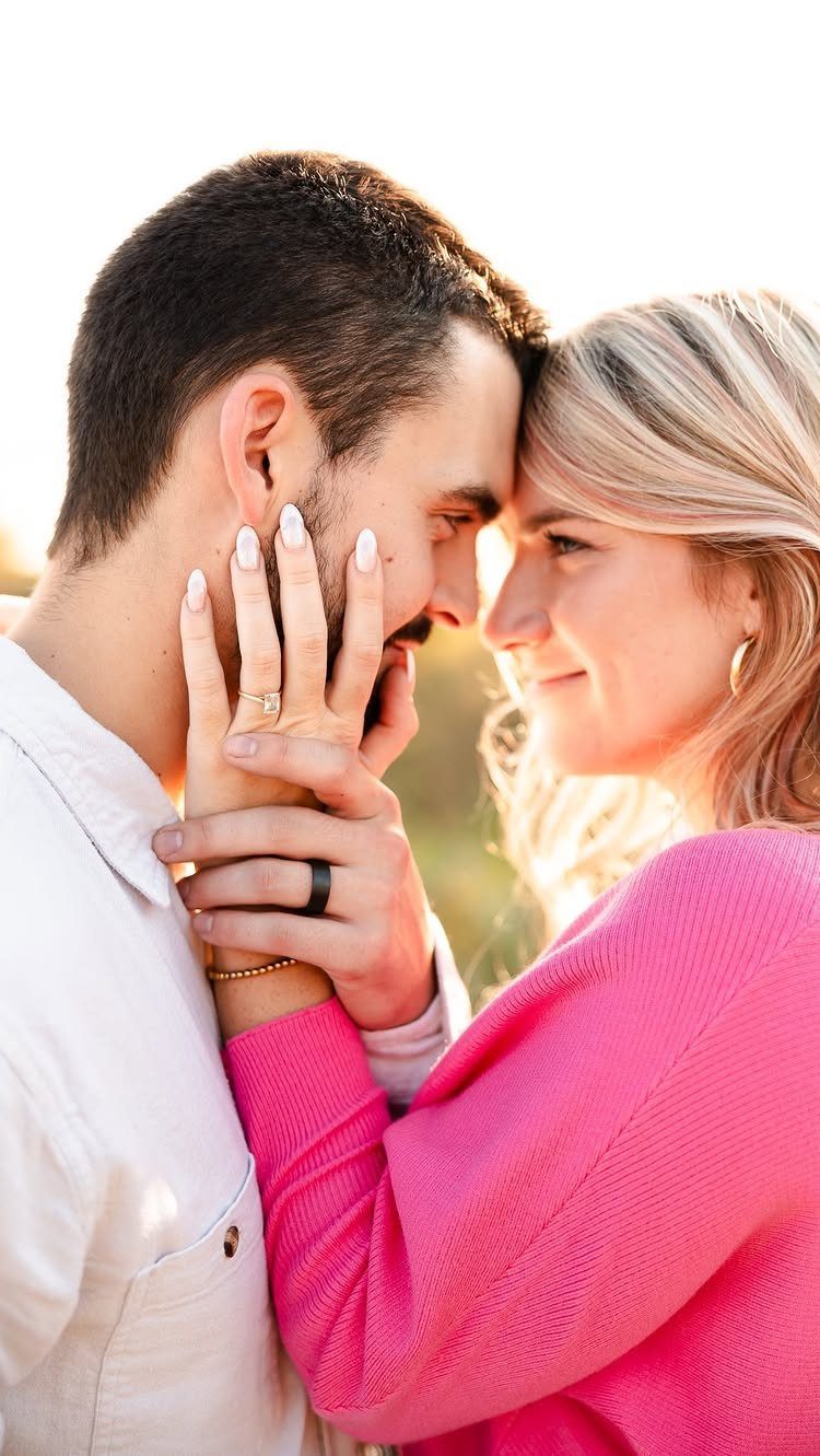 Couple touching foreheads with woman's hand on man's cheek in a romantic pose.