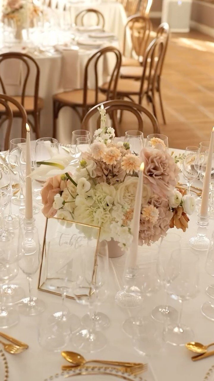 Wedding table setting with cream and latte colored flowers, gold cutlery, and candles.