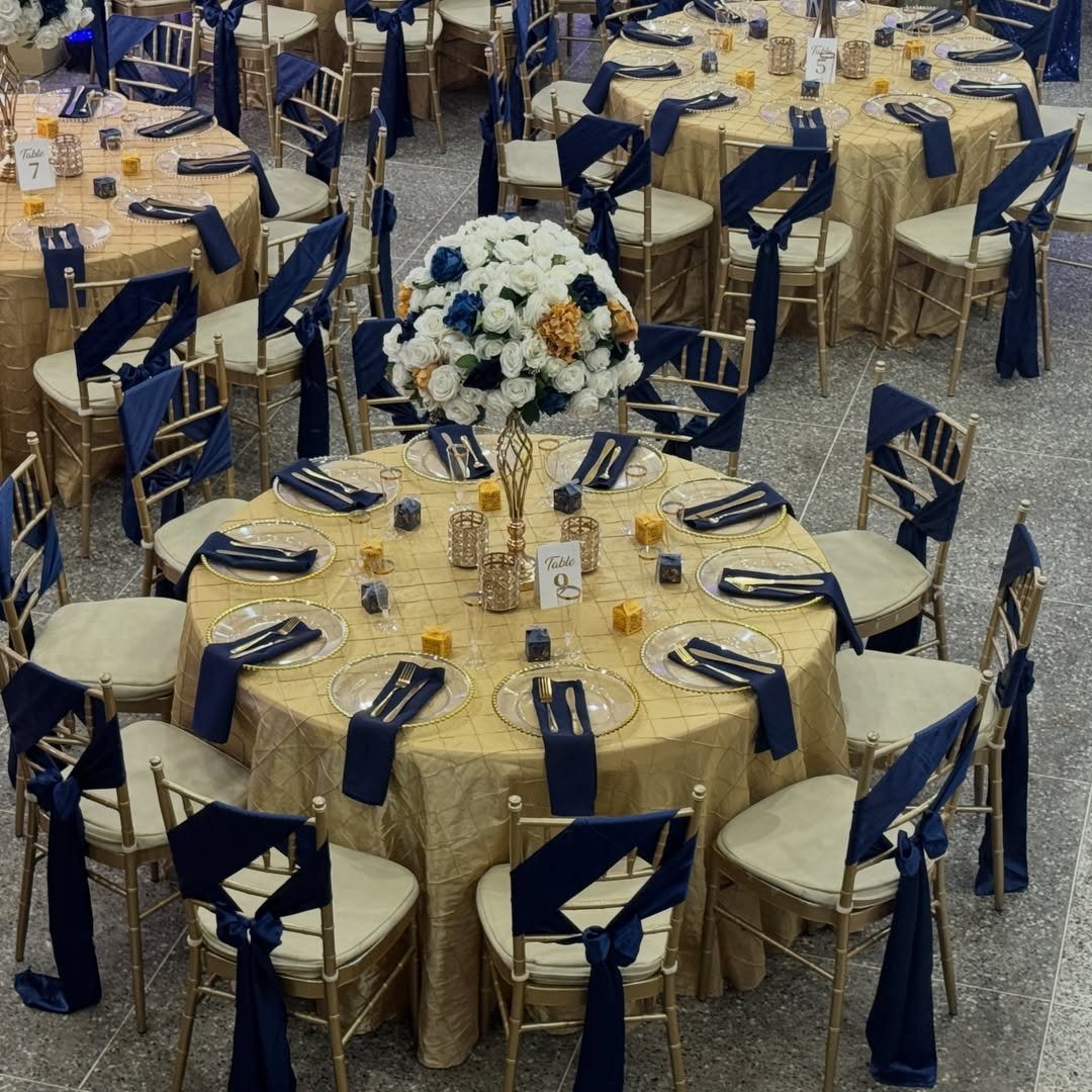 Champagne gold tablecloths and navy blue chair sashes at a formal wedding reception.
