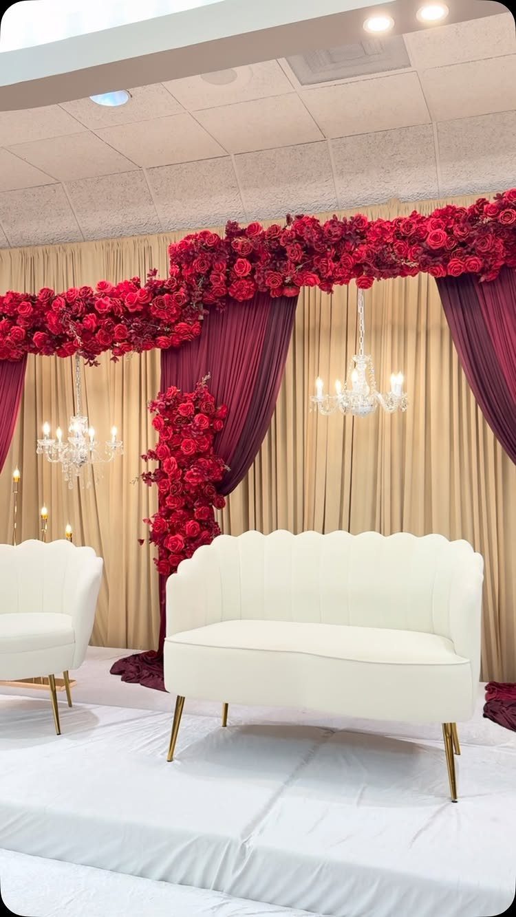 White scalloped sofa and red rose floral arrangements at a wedding reception venue.