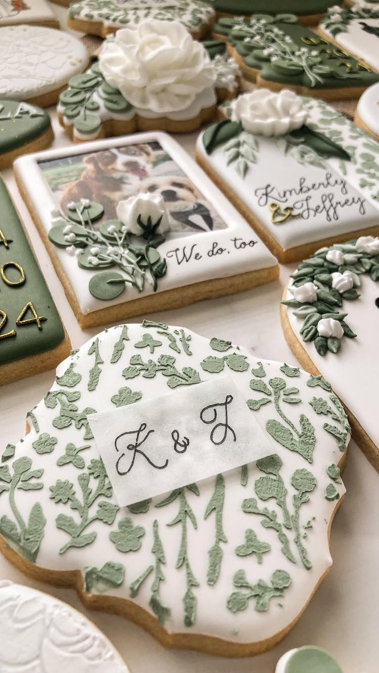 Sage green and white decorated wedding cookies with floral icing and calligraphy.