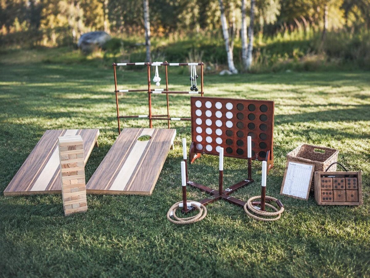 25 Wedding Stuff Ideas for Your 2026 Ceremony and Party 12 Wooden lawn games like cornhole and Connect Four arranged on a sunny grass field.