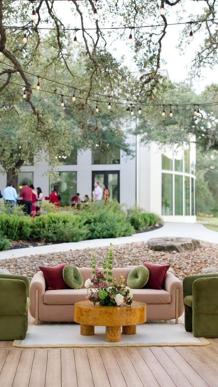 25 Wedding Stuff Ideas for Your 2026 Ceremony and Party 13 Outdoor lounge set with a pink sofa, green armchairs, and a floral centerpiece on a wooden deck.