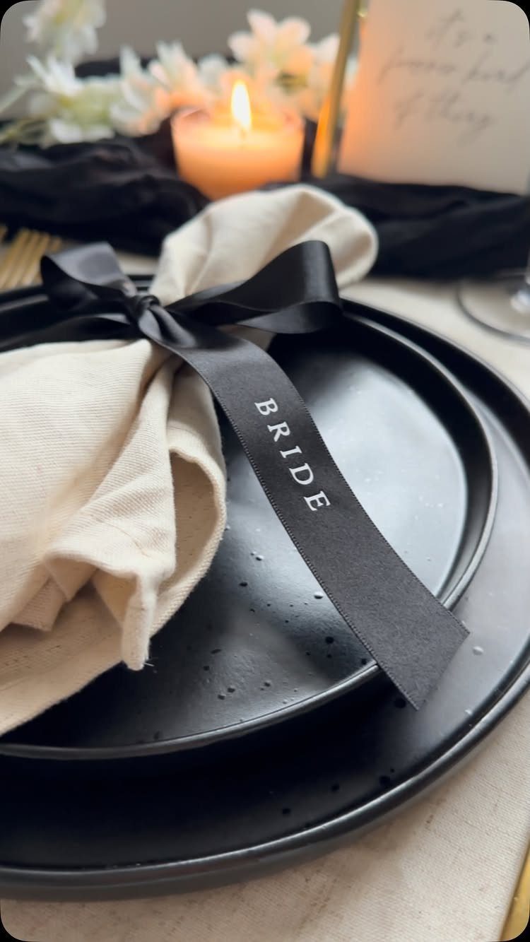 25 Wedding Stuff Ideas for Your 2026 Ceremony and Party 26 Black plate with a cream napkin tied by a black ribbon printed with the word BRIDE.