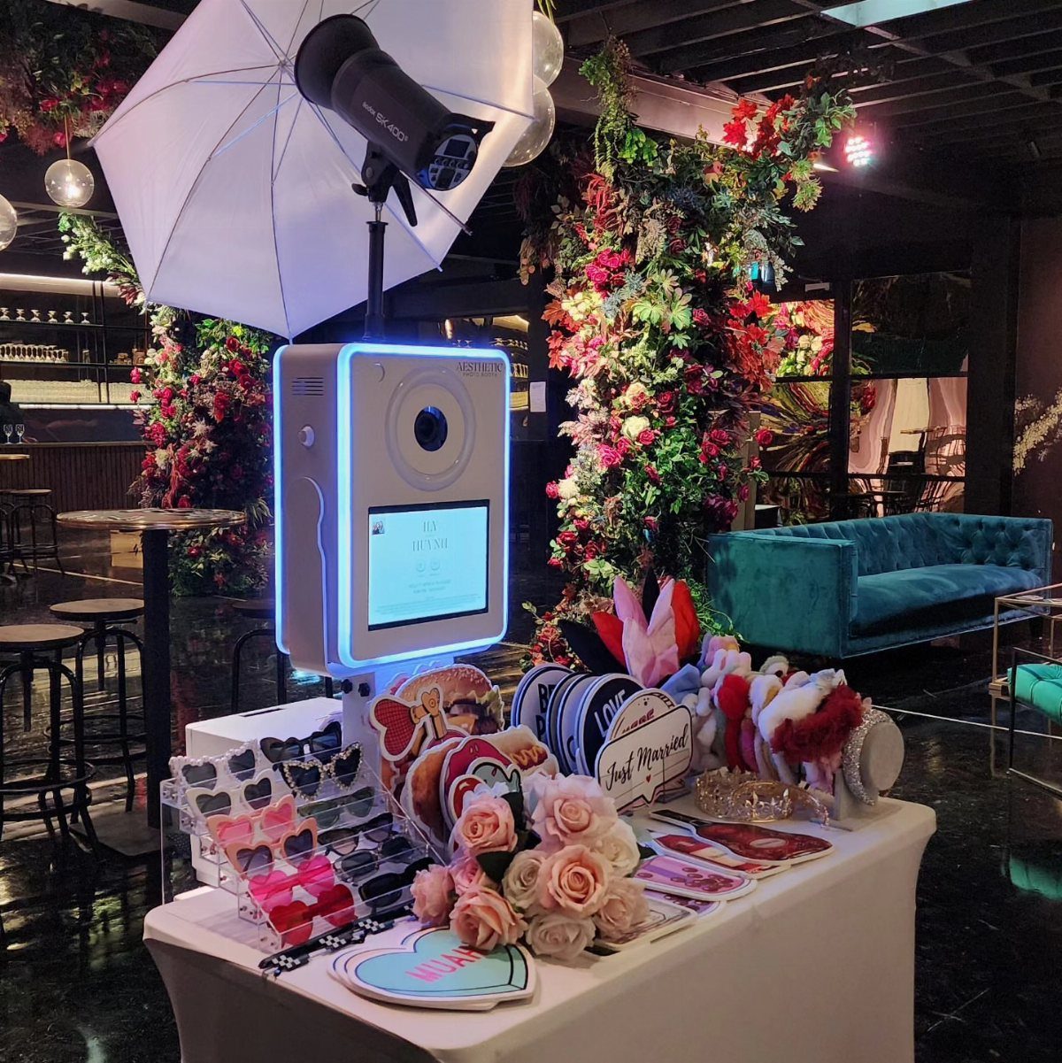 25 Wedding Stuff Ideas for Your 2026 Ceremony and Party 19 Digital photo booth machine with various props on a table in a decorated event space.