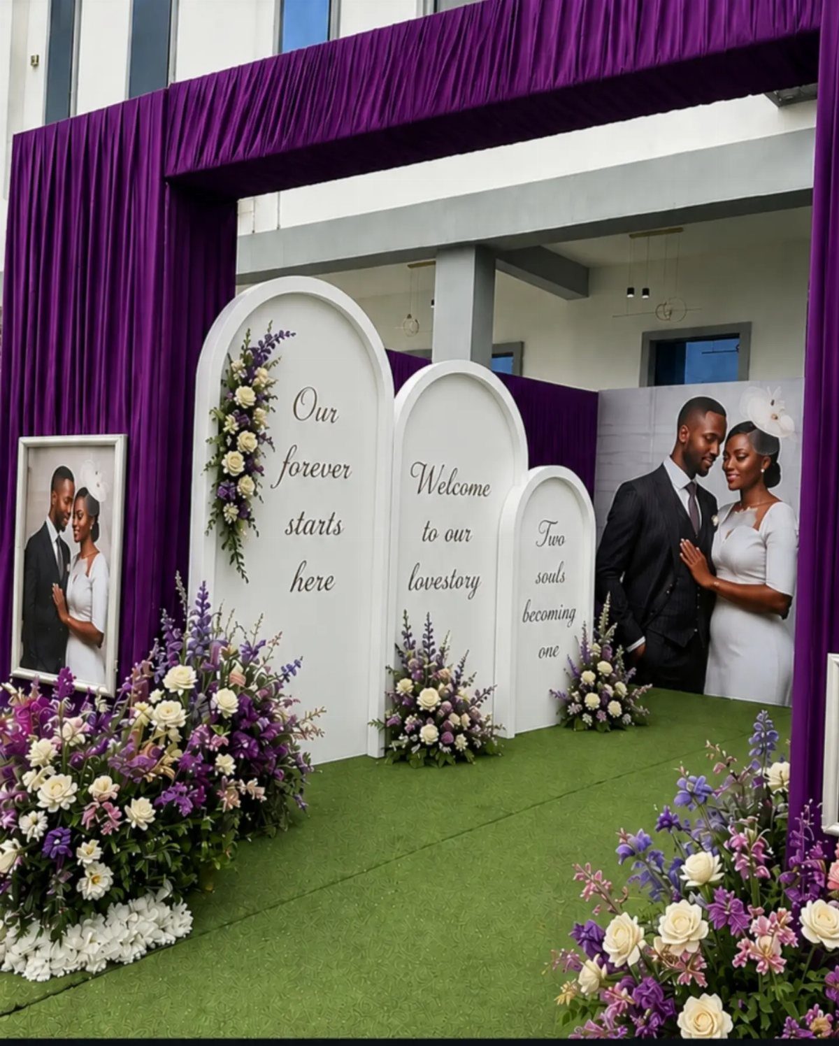25 Wedding Stuff Ideas for Your 2026 Ceremony and Party 3 White arched wedding backdrop panels with floral arrangements and purple fabric draping on green grass.