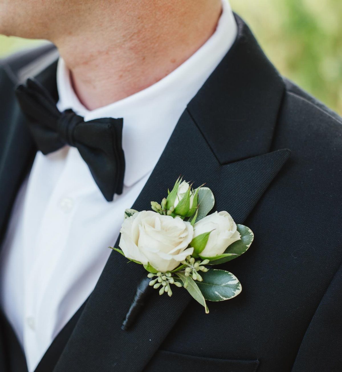 Wedding Theme Flowers: 21 Ideas for Ceremony to Cake 18 White rose boutonniere pinned to the black lapel of a man in a tuxedo.
