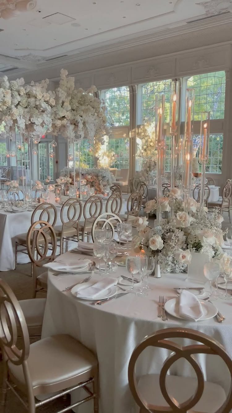 Wedding Theme Flowers: 21 Ideas for Ceremony to Cake 19 White floral centerpieces with tall candles set on elegant wedding reception tables with gold chairs.
