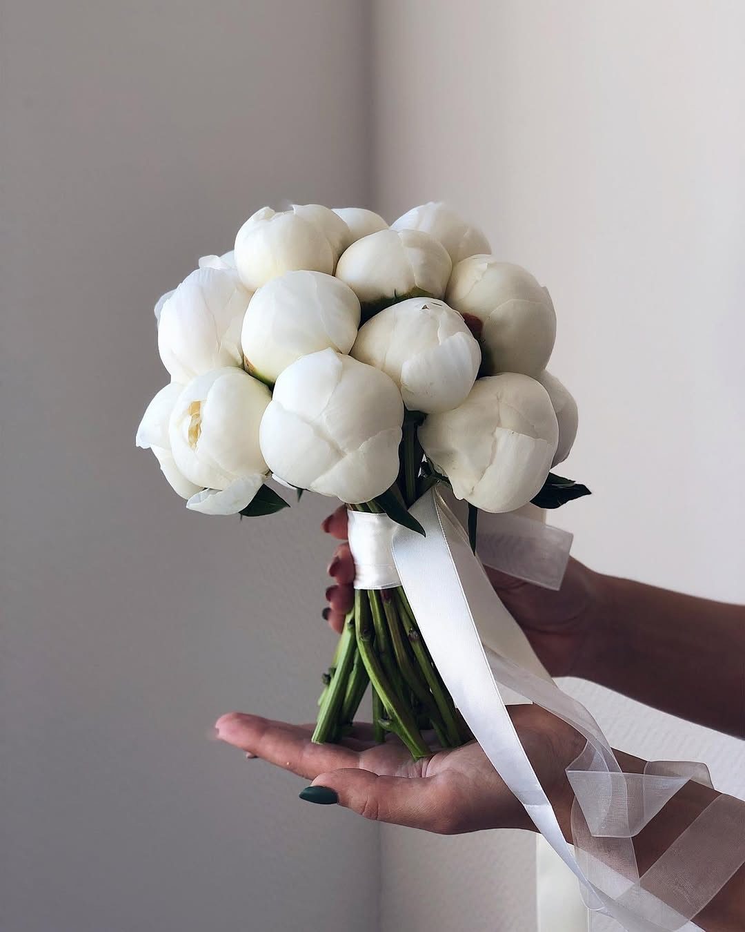 Wedding Theme Flowers: 21 Ideas for Ceremony to Cake 3 A bouquet of white peonies held by hands with long white ribbons hanging down.