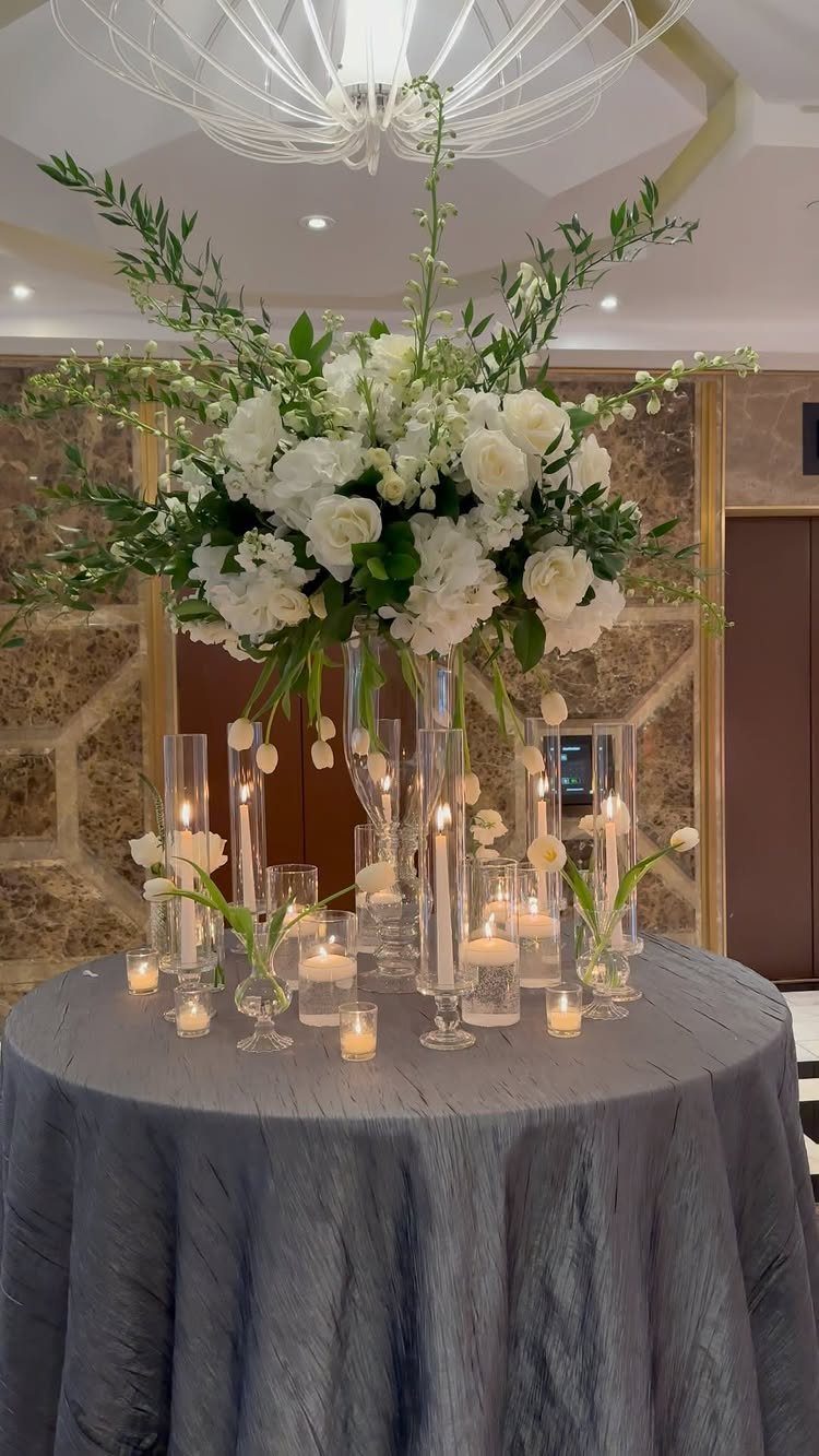Wedding Theme Flowers: 21 Ideas for Ceremony to Cake 2 Large white rose and hydrangea floral centerpiece with lit candles on a grey tablecloth.