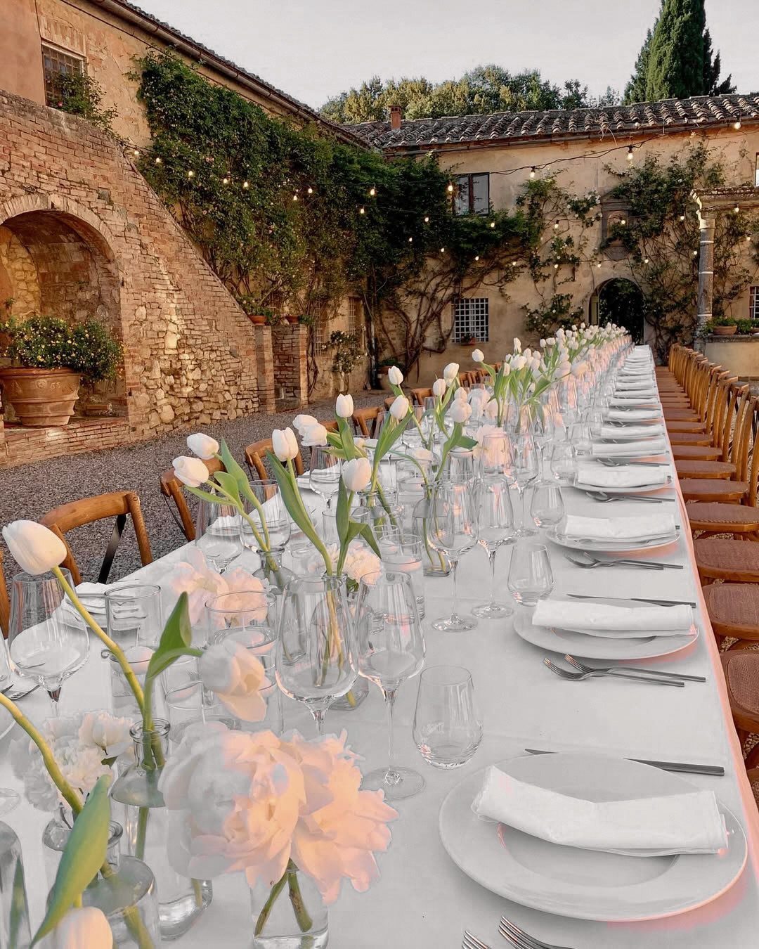 Wedding Theme Flowers: 21 Ideas for Ceremony to Cake 10 White and pink tulips in glass vases arranged along a long, elegantly set outdoor dining table.