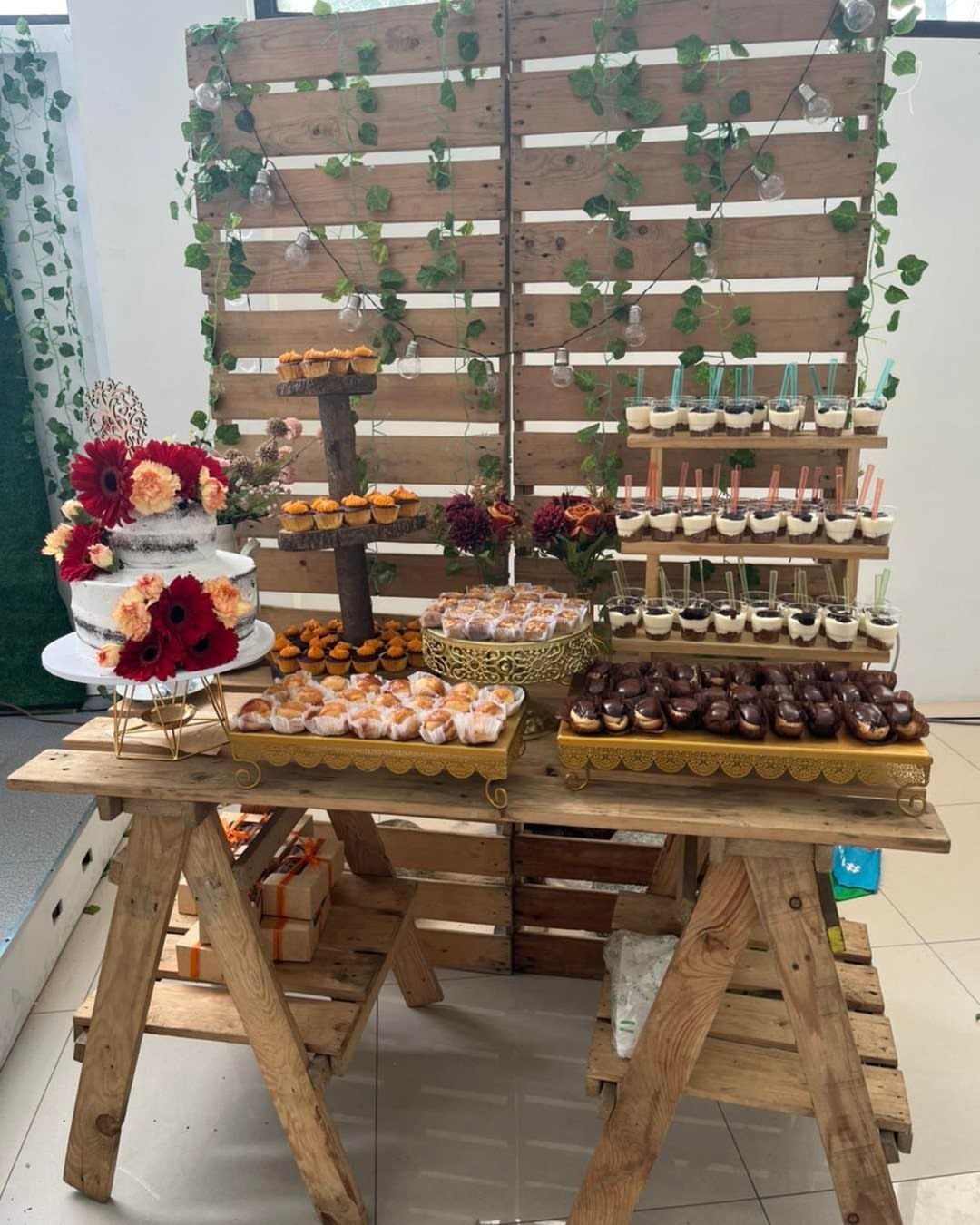 Wedding Theme and Motif: 16 Fresh Ideas for 2026 2 A dessert table with a white floral cake and various pastries on a rustic wooden trestle.