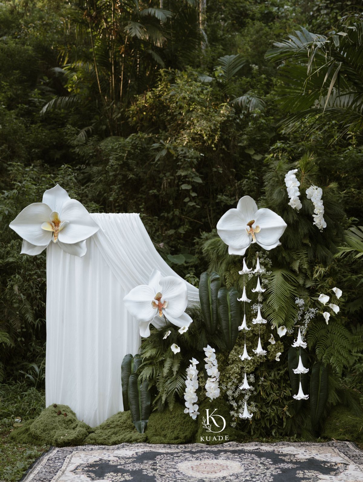 Wedding Theme and Motif: 16 Fresh Ideas for 2026 8 White orchids and draped fabric arranged with lush green ferns in a tropical forest setting.