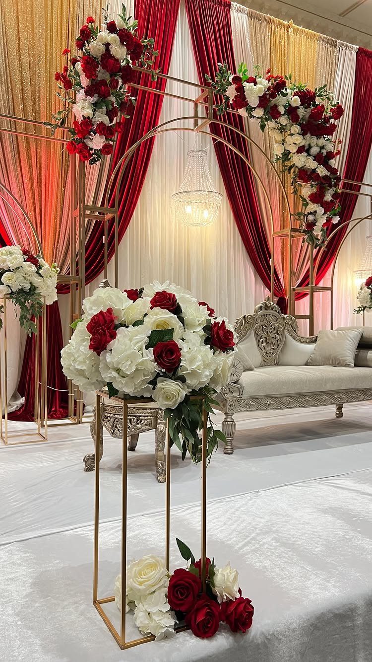 8 Wedding Theme Red and Gold Ideas for Every Part of Your Day 4 Gold metal wedding arch decorated with red and white roses in front of red and gold drapes.